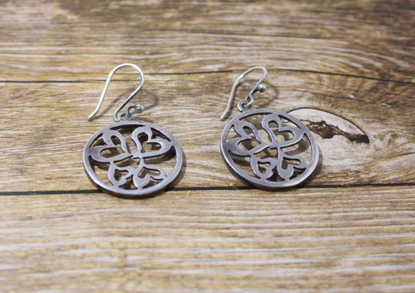 Gümüş küpe karanlık bir arka plan üzerinde yuvarlak bir formun. Kadınlar için tatil için harika bir hediye.