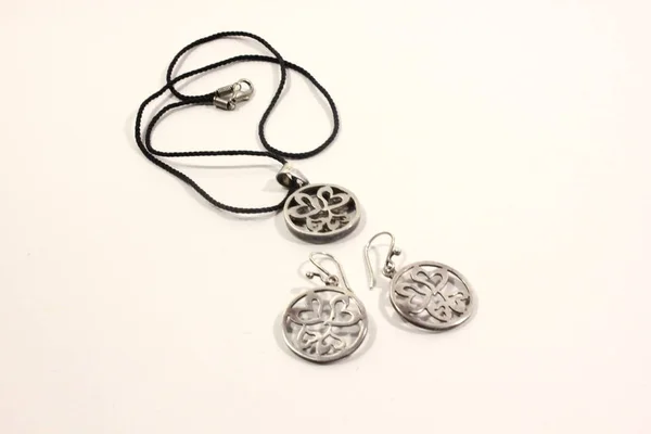 Mücevher gümüş - bir kolye bir kordon ve küpe yuvarlak bir form üzerinde beyaz bir arka plan üzerinde yapılan bir dizi.