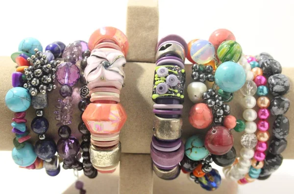 Doğal yarı değerli taşları bir stand üzerine yapılan pek çok el bilezikler.