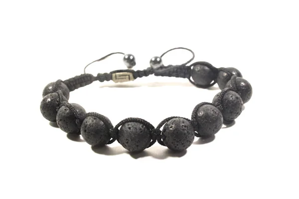 Beyaz bir arka plan üzerinde siyah gözenekli taşlarla erkekler için el yapımı bilezik.