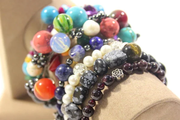 Bir sürü el yapımı takı doğal yarı değerli taşlar beyaz zemin üzerinde bir stand ile.