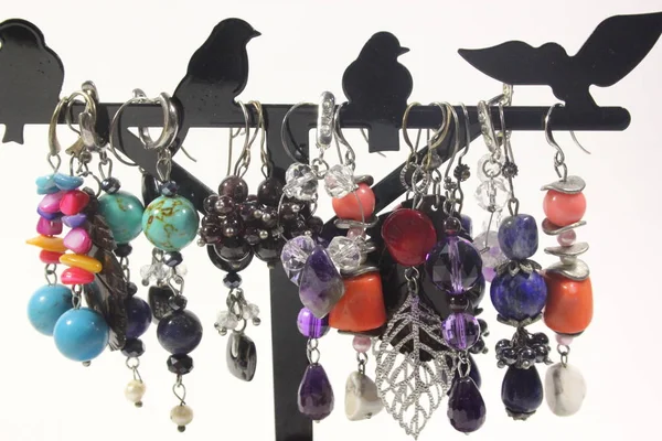 Bir sürü beyaz zemin üzerinde bir stand doğal yarı değerli taşlar ile el yapımı takılar. Küpe, bilezik ve kolye.