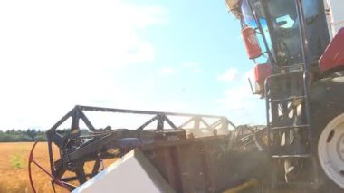 Sıcak güneşli bir sonbahar günde, çiftçiler tahıl ürünleri hasat biçerdöverler ile.