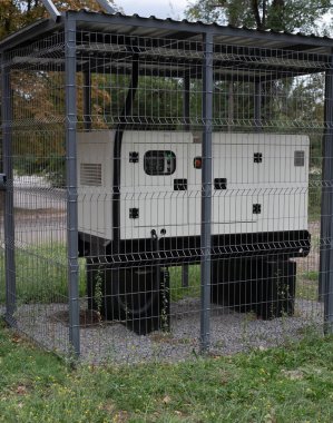 Installation of a large industrial fuel-fired generator on a green lawn. A mobile power source, backup equipment for power plants. 