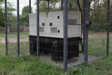 Installation of a large industrial fuel-fired generator on a green lawn. A mobile power source, backup equipment for power plants. 