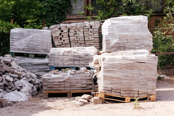 White bricks stacked on wooden pallets at a construction site. 