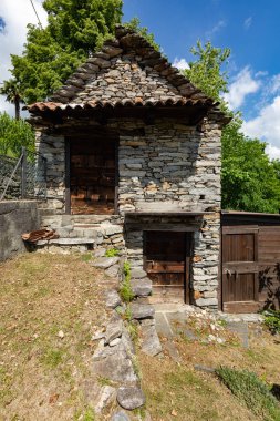 Büyük bir çiçek bahçesi içinde taş kulübe. İçeride kimse yok