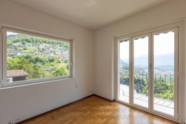 Boş beyaz oda parke ve İsviçre hills bakan büyük pencereler ile. İçeride kimse yok