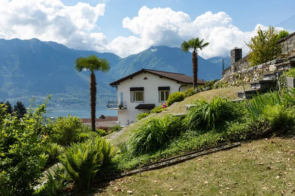 Exterior of villa with large green garden. View of hills and lake. Nobody inside