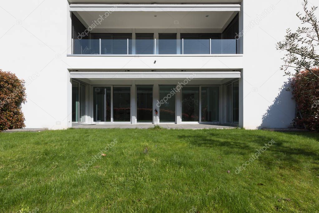 Modern house exterior with well-kept green lawn. Sunny day