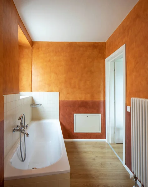 Bathroom with modern finishes and orange walls. Nobody inside