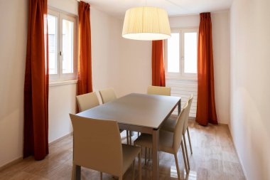 Deri sandalye ile zarif yemek odası. İki pencere ile kırmızı perdeler. İçeride kimse yok