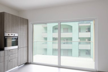 Geniş oturma odası ve modern bir açık alanda tamamen beyaz mutfak. İçeride kimse yok