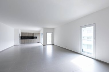 Geniş oturma odası ve modern bir açık alanda tamamen beyaz mutfak. İçeride kimse yok