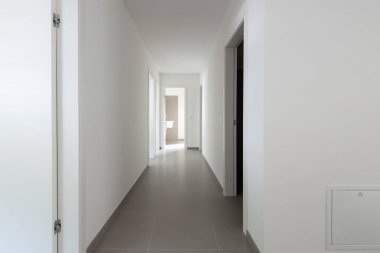 Birçok açık kapı ile beyaz koridor. İçeride kimse yok