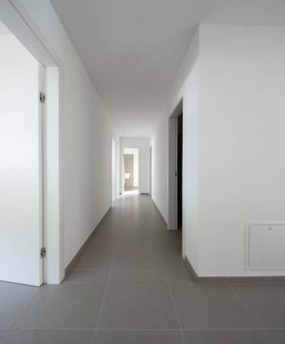 Birçok açık kapı ile beyaz koridor. İçeride kimse yok