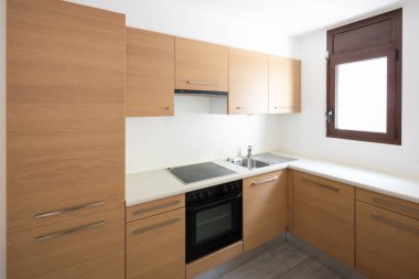 Modern mutfak ahşap ve beyaz duvarlar, küçük bir pencere. İçeride kimse yok