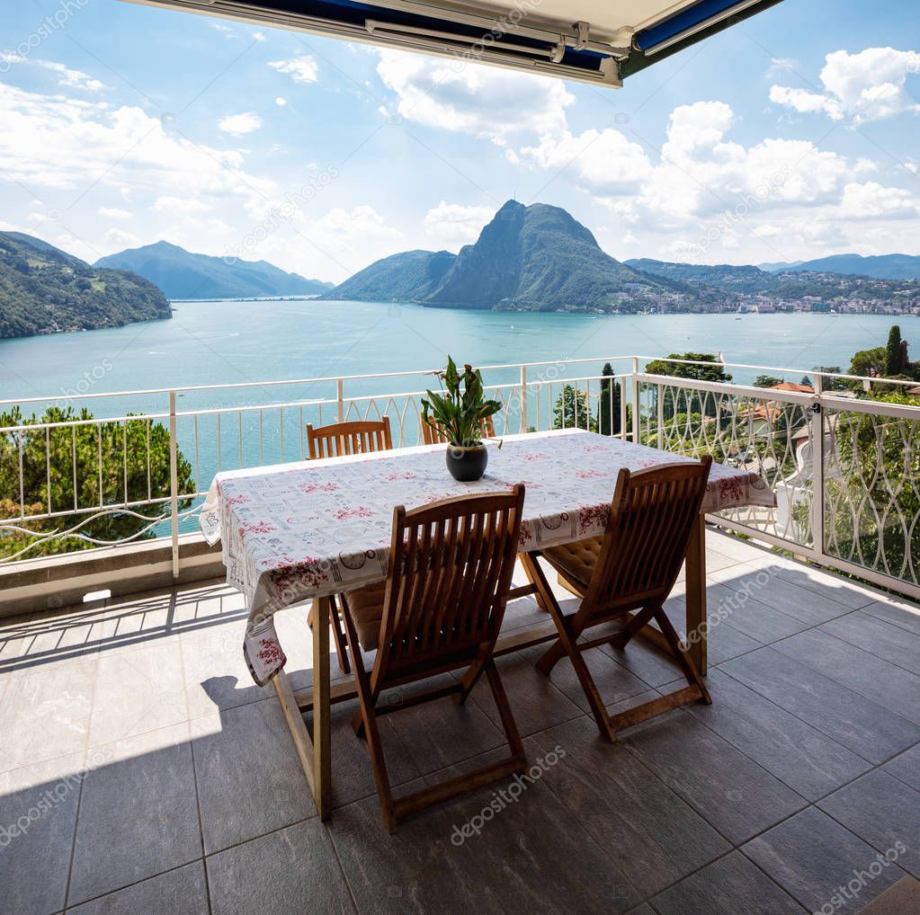 Large terrace overlooking the lake of Lugano on a summer day. Nobody inside