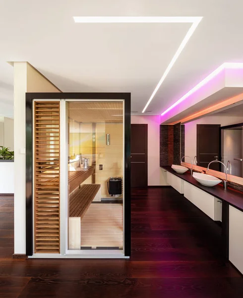 Glass and wood sauna in modern villa. Colored LEDs and nobody inside
