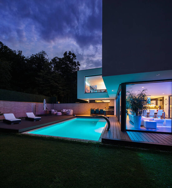 Современная вилла с цветными светильниками ночью. Никого внутри
