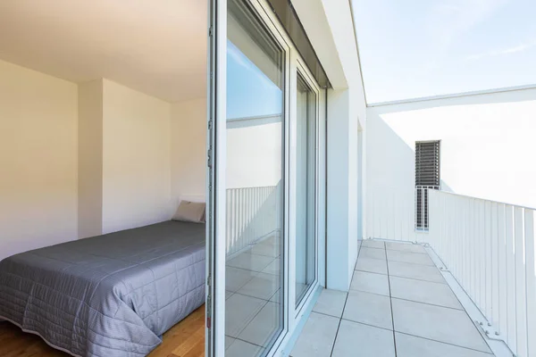 Balcony and bedroom together with a window open