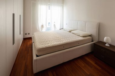 Büyük dolap ve parlak pencere ile yatak odası. İçeride kimse yok