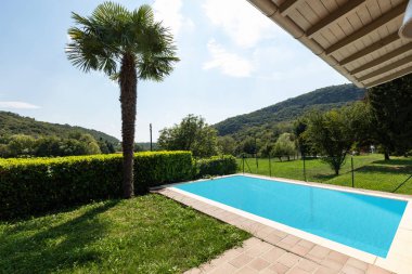 Havuzlu Villa ve bir yaz gününde tarafından yeşil çim çevrili. İçeride kimse yok