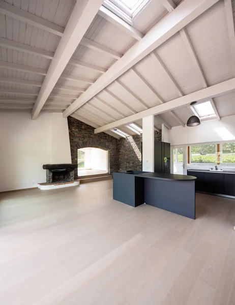 Empty living room with dark kitchen and island, wooden beams