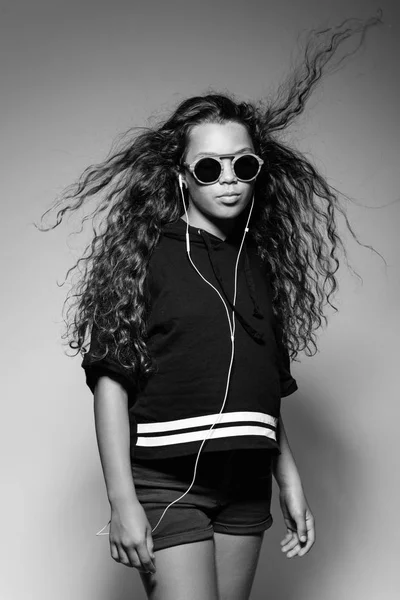 Young woman with headset in ears and sunglasses. Wind gust. Studio portrait