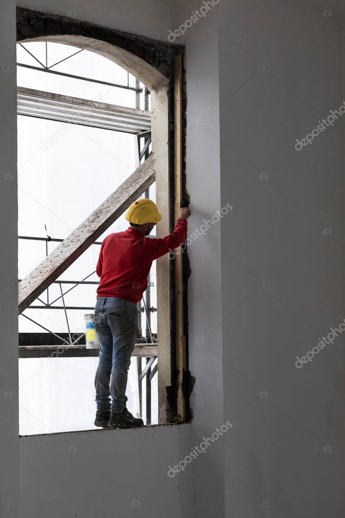 Worker balancing on a window while working. Building site