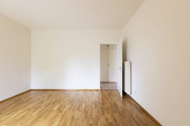 Beyaz duvarları, parke zemin ve ahşap kapı ile boş oda. Kopya alanı