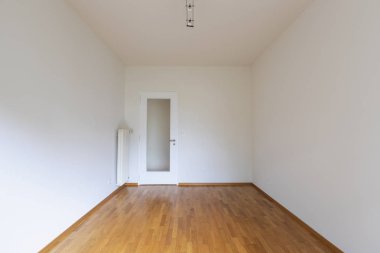 Beyaz duvarları, parke zemin ve ahşap kapı ile boş oda. Kopya alanı