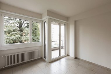 Boş oda, doğa bakan büyük pencereler. İçeride kimse yok