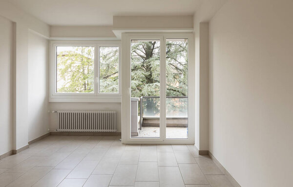 Empty room with radiators and large windows overlooking nature. Front view