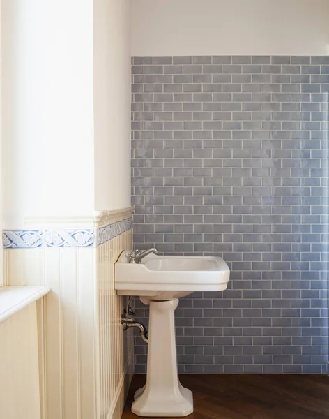 Detail of a porcelain sink with light blue tiles. Nobody inside