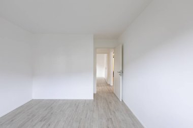 Beyaz duvarları ve açık kapı sağ taraftaki boş oda. İçeride kimse yok