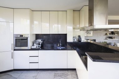 Beyaz mutfak siyah mermer üst ve büyük başlık ile. İçeride kimse yok