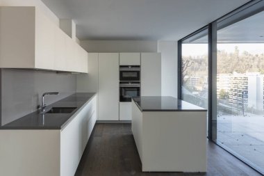 Modern beyaz mutfak büyük pencereler ile önden görünümü ve şehir manzaralı. İçeride kimse yok