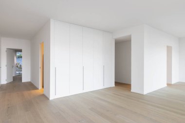 Koridor yerleşik dolapları, beyaz duvarlar ve parke. İçeride kimse yok