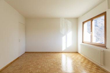 Sadece bir pencere ile boş bir odanın iç. Biz küçük bir radyatör ve ahşap zemin görebilirsiniz