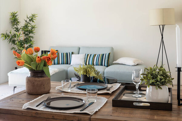 Wooden table detail with plates, cutlery and bunch of orange tul