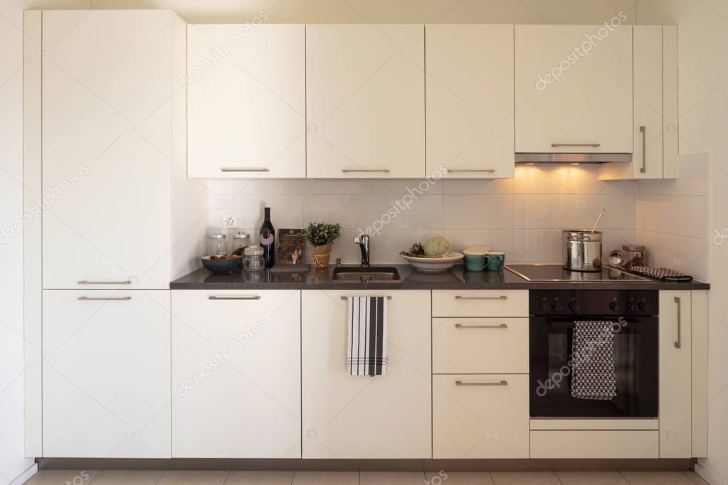 Front view of white modern kitchen with lights on