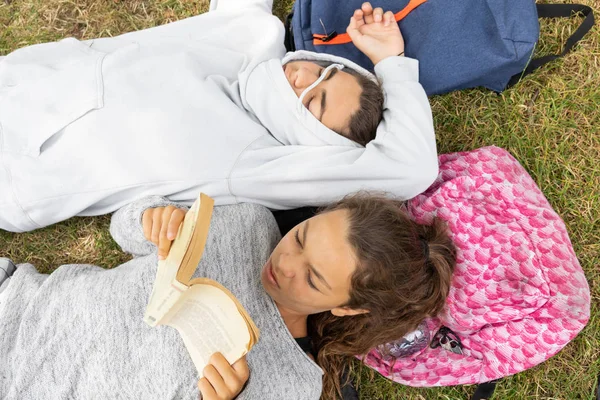 Girl reads a book and boy sleeps at the park. — Stock Photo, Image