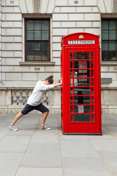 Un garçon pousse une boîte d'appel rouge à Londres — Photo