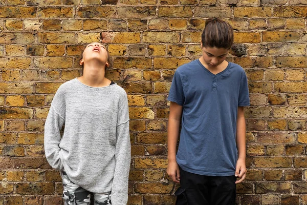 Deux jeunes adolescents déprimés se tiennent devant un mur de briques — Photo