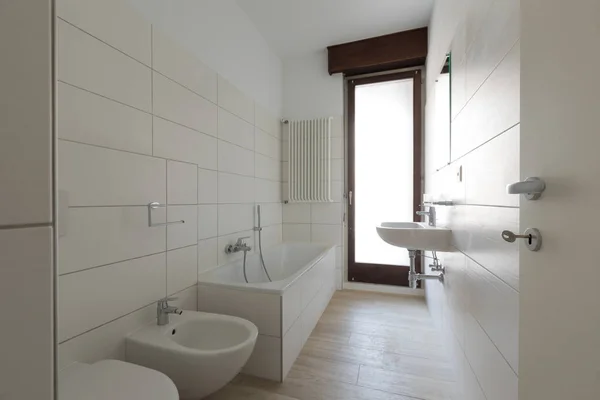 Современная отремонтированная ванная комната с большими плитками и окнами — стоковое фото