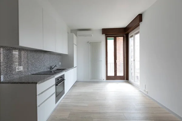 Velký prázdný pokoj s bílými stěnami a moderní kuchyní. — Stock fotografie