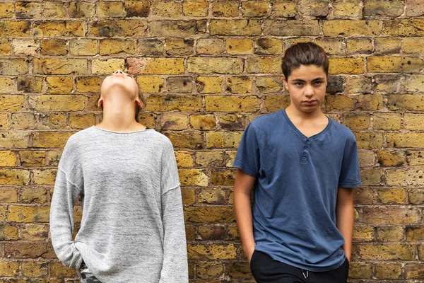 Dois jovens adolescentes deprimidos ficam em frente a uma parede de tijolo — Fotografia de Stock
