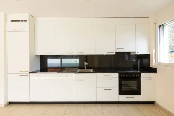 Prázdný pokoj s bílými stěnami, travertinovou podlahou a bílou kuchyní — Stock fotografie