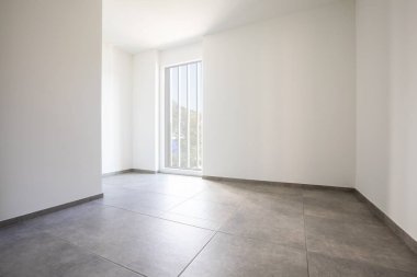 Beyaz duvarları ve parlak penceresi olan boş bir oda